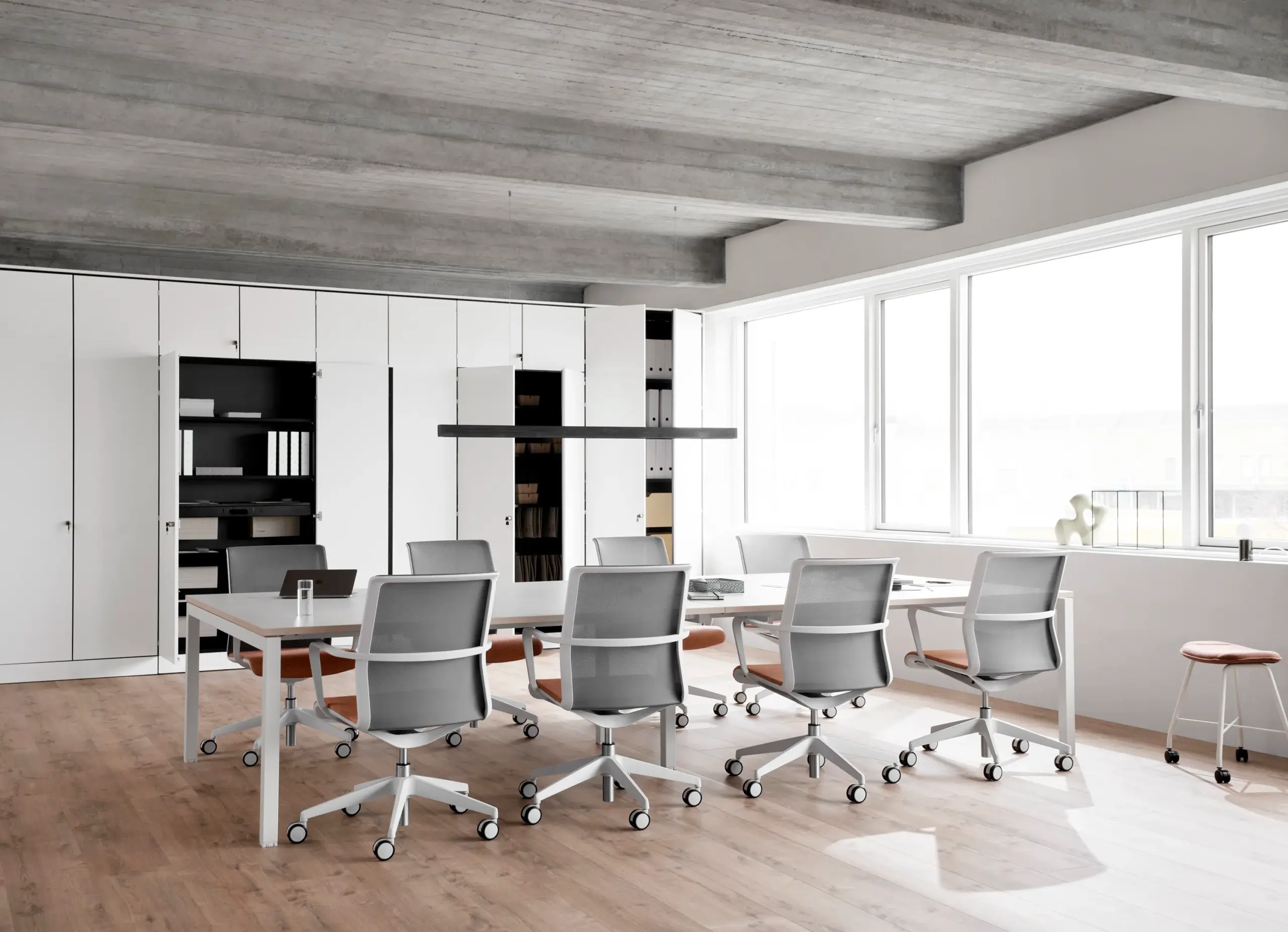 Modern office meeting room with ergonomic chairs, white tables, and built-in storage cabinets